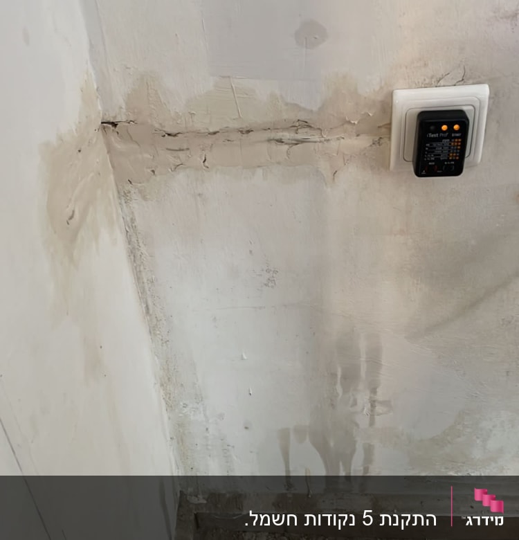 שקע חשמלי בקיר עם מכשיר בדיקה